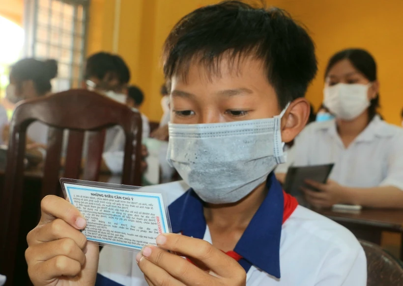 Học sinh có hoàn cảnh khó khăn nhận thẻ bảo hiểm từ nhà hảo tâm. Ảnh: Duy Khương - TTXVN
