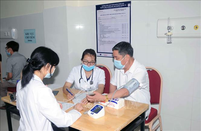 Trước khi tiêm, các đối tượng được đo thân nhiệt, huyết áp, khai báo tiền sử bệnh lý và được bác sĩ thăm khám, tư vấn chu đáo. Ảnh: Quang Quyết-TTXVN