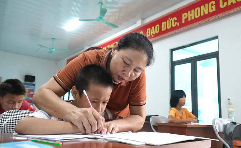 Cô giáo Hoàng Thị Vỵ dạy chữ cho trẻ bị khuyết tật. Ảnh: Việt Dũng - TTXVN