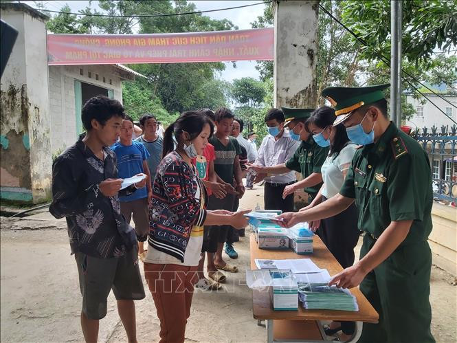 Người dân xã Xín Cái thực hiện rửa tay sát khuẩn và nhận khẩu trang trước khi vào nghe tuyên truyền phổ biến pháp luật về xuất, nhập cảnh. Ảnh: Nguyễn Chiến - TTXVN