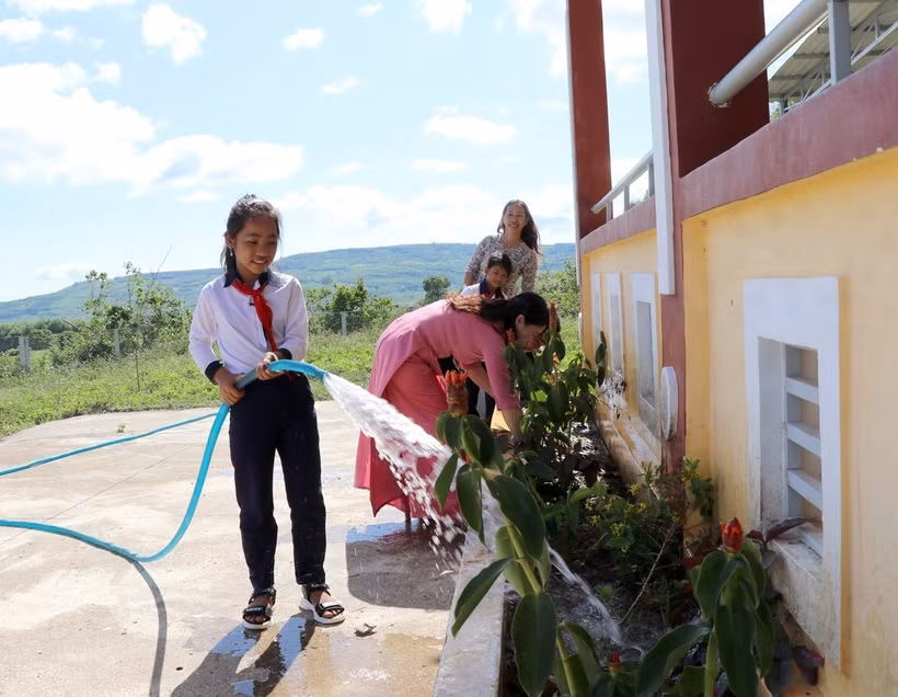 Cô và trò tại điểm trường thôn Hòa Ngãi sử dụng nước từ giếng khoan để chăm sóc hoa trong khuôn viên. Ảnh: Xuân Triệu - TTXVN