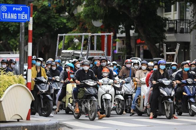 Thành phố Hà Nội đã nới lỏng giãn cách được gần 1 tháng, cuộc sống của người dân đã dần ổn định trở lại bình thường. Trong ảnh: Những người tham gia giao thông dừng đèn đỏ đều tuân thủ đeo khẩu trang phòng chống dịch vừa là bảo vệ sức khỏe tránh ô nhiễm c