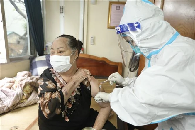 Nhân viên y tế phường Cửa Đông (quận Hoàn Kiếm) tiêm cho người cao tuổi tại nhà. Ảnh: Minh Quyết - TTXVN 