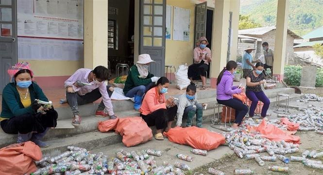Thành viên Câu lạc bộ “Vệ sinh môi trường” và bà con bản Lun 1, xã Tà Mung, huyện Than Uyên (Lai Châu) làm gạch sinh thái xây dựng tường bao, cổng chào nhà văn hóa của bản. Ảnh: Việt Hoàng-TTXVN 