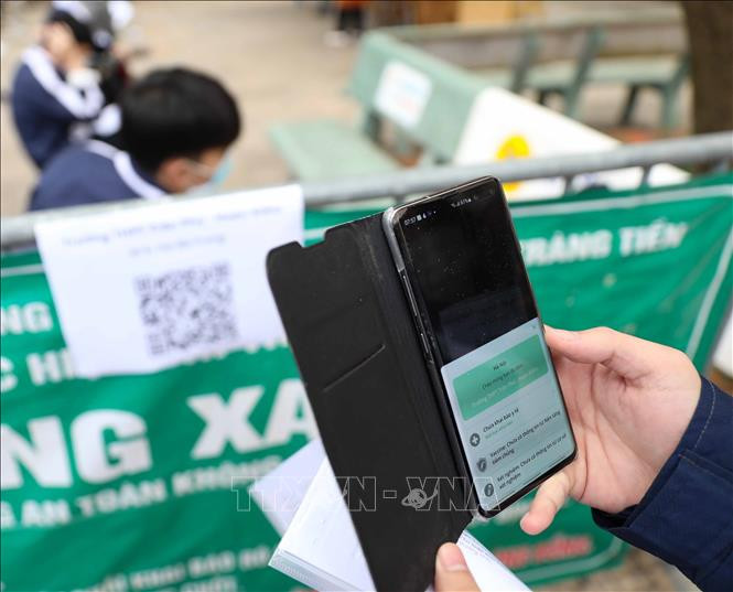 Học sinh tới điểm tiêm Trường THPT Trần Phú thực hiện đo thân nhiệt, sát khuẩn tay và quét mã. Ảnh: Thanh Tùng - TTXVN