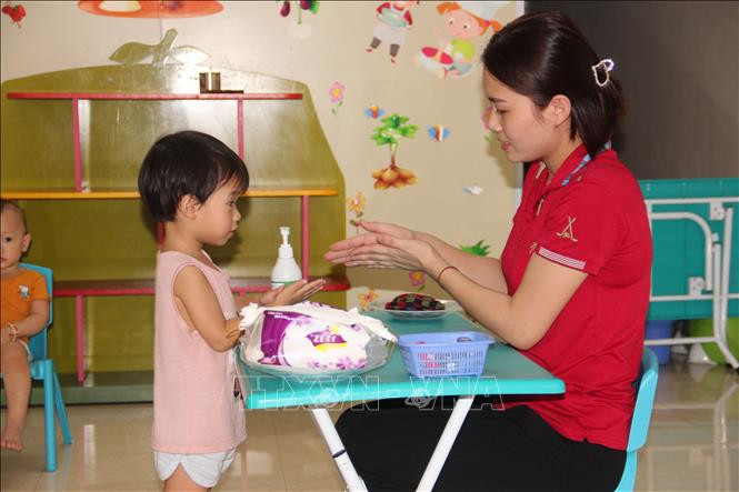 Các bé thuộc nhóm trẻ tư thục Ánh Sao được cô giáo hướng dẫn rửa tay sát khuẩn. Ảnh: Hoàng Ngà - TTXVN