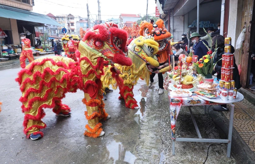 Đội lân sư rồng thuộc đoàn rước ghé vào các mâm lễ của các gia đình hai bên đường chúc làm ăn đắc lộc trong những ngày diễn ra lễ hội truyền thống đền Kỳ Cùng - Tả Phủ. Ảnh: Anh Tuấn – TTXVN