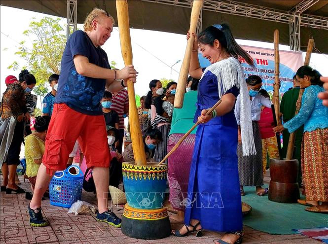 Du khách nước ngoài thích thú trải nghiệm giã cốm dẹp tại Tết quân dân. Ảnh: Thu Hiền - TTXVN