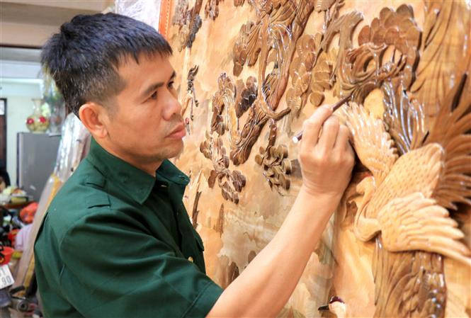 Nghệ nhân ưu tú Nguyễn Văn Hùng hoàn thiện bức tranh ghép gỗ. Ảnh: Đinh Văn Nhiều - TTXVN 