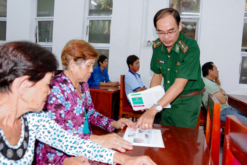 Cán bộ biên phòng cấp phát tờ rơi tuyên truyền cho bà con nhân dân dự hội nghị. Ảnh: baosoctrang.org.vn
