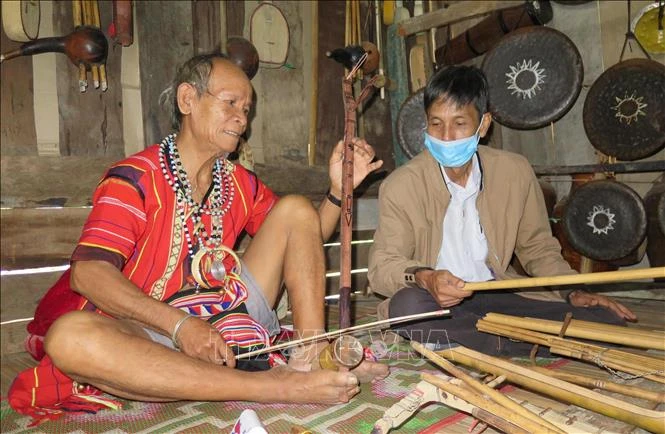 Nghệ nhân ưu tú A Brol Vẽ (áo đỏ, sinh năm 1945, già làng Đắk Răng, xã Đắk Dục, huyện Ngọc Hồi, tỉnh Kon Tum) được phong tặng Nghệ nhân ưu tú năm 2015 nhưng không nhận được mức hỗ trợ hàng tháng. Ảnh: Dư Toán – TTXVN