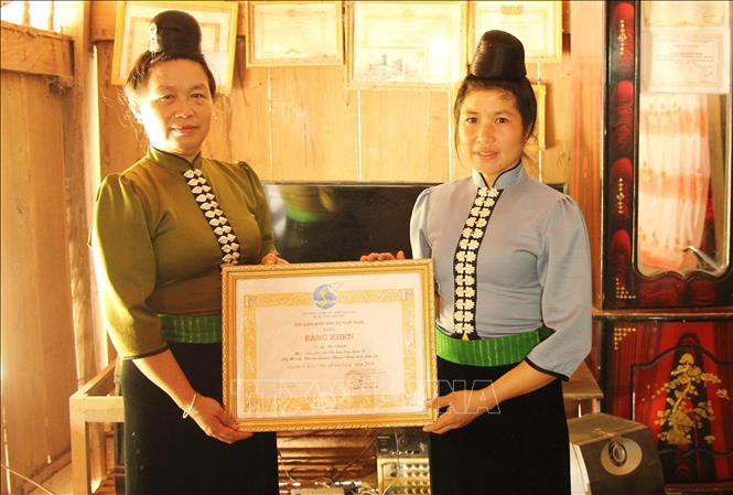 Chị Lò Thị Sao, Chủ tịch Hội Liên hiệp Phụ nữ xã Mường Khiêng trao Bằng khen "Phụ nữ tiêu biểu" của Trung ương Hội Liên hiệp Phụ nữ Việt Nam cho chị Quàng Thị Nhín. Ảnh: Nguyễn Cường - TTXVN