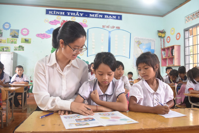 Cô H Pa Ra Ayŭn hướng dẫn học sinh trường Tiểu học Võ Thị Sáu, xã Cư Dliê Mnông (Cư M’gar, Đắk Lắk) làm bài. Ảnh: Nguyên Dung/TTXVN giao-vien1-1605.jpg