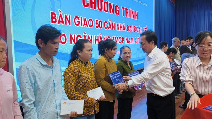 Trao bảng tượng trưng và quà cho người dân được nhận nhà mới. Ảnh: Huỳnh Phúc Hậu/TTXVN ben-tre2-3105.jpg