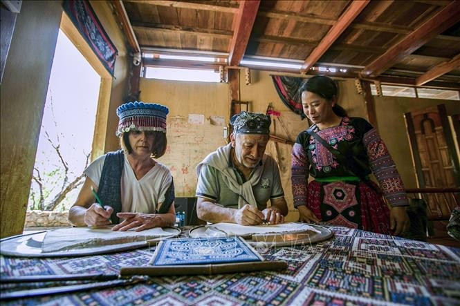 Du khách Pháp trải nghiệm vẽ sáp ong trên vải thổ cẩm người Mông tại Homestay Y Múa xã hang Kia. Ảnh tư liệu: Trọng Đạt/TTXVN hang-kia-131124-4.jpg