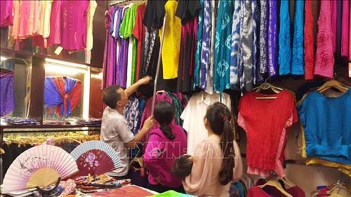 Khách hàng bị cuốn hút bởi những sản phẩm dệt lụa truyền thống Vạn Phúc. Ảnh: Đinh Thuận - TTXVN
