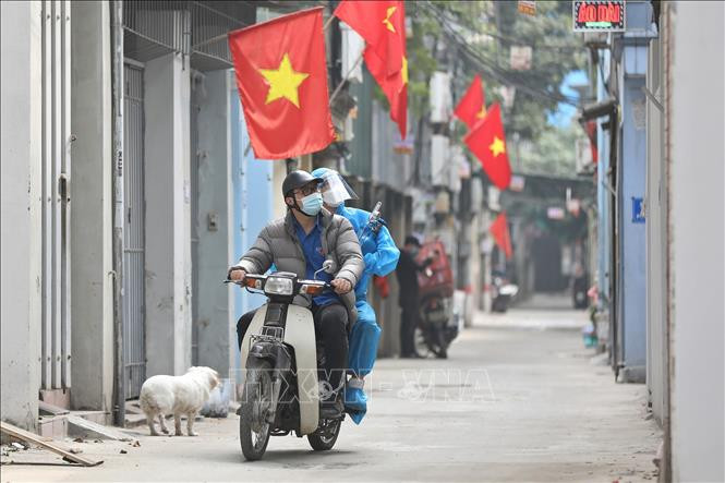 Thành viên Tổ hỗ trợ theo dõi người nhiễm COVID-19 tại nhà ở phường Lĩnh Nam được trang bị đồ bảo hộ, chở oxy bằng xe máy đến tận nhà người bệnh. Việc sử dụng "ATM Oxy" là hoàn toàn miễn phí. Ảnh: Minh Quyết – TTXVN