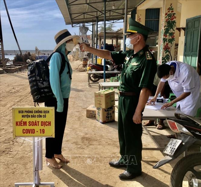 Các cán bộ, chiến sỹ Biên phòng đảo Cồn Cỏ đo nhiệt độ những người dân và hành khách lên đảo. Ảnh: TTXVN