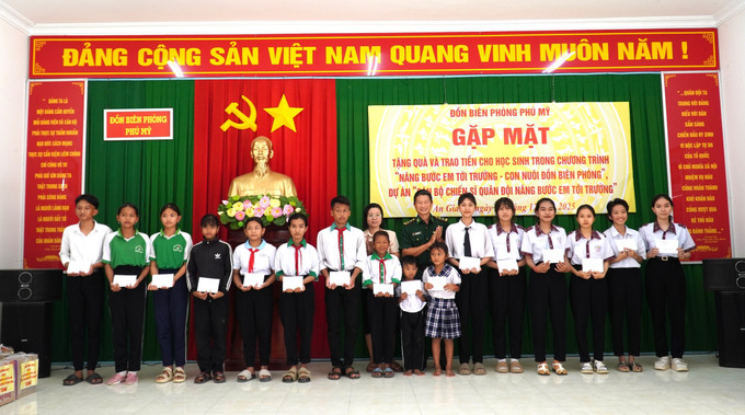 Trung tá Bùi Thanh Ngàn, Đồn trưởng Đồn Biên phòng Phú Mỹ trao quà cho các học sinh thuộc dự án “Cán bộ chiến sĩ Quân đội nâng bước em đến trường”.