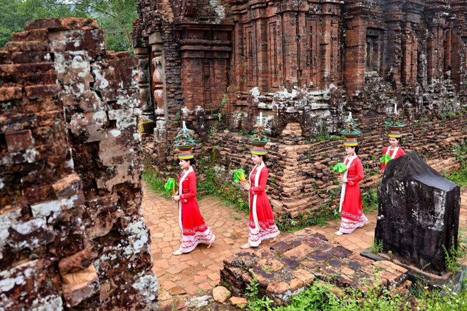 Trang phục truyền thống rực rỡ của vũ công Chăm nổi bật trên nền gạch cổ kính, tạo nên sự tương phản độc đáo. vu-dieu-cham-1.jpg
