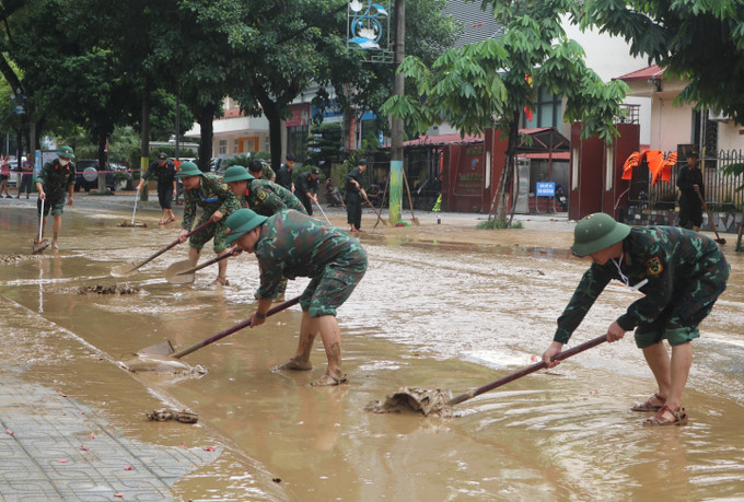 Lực lượng chức năng dọn dẹp bùn đất tại những đoạn đường phố nước đã rút. Ảnh: Chu Hiệu/TTXVN Lực lượng chức năng dọn dẹp bùn đất tại những đoạn đường phố nước đã rút. Ảnh: Chu Hiệu/TTXVN