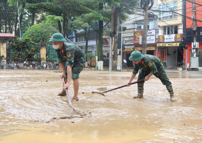 Lực lượng chức năng dọn dẹp bùn đất những đoạn đường phố nước đã rút. Ảnh: Chu Hiệu/TTXVN Lực lượng chức năng dọn dẹp bùn đất những đoạn đường phố nước đã rút. Ảnh: Chu Hiệu/TTXVN