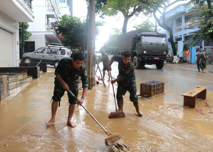 Lực lượng chức năng dọn dẹp bùn đất những đoạn đường phố nước đã rút. Ảnh: Chu Hiệu/TTXVN Lực lượng chức năng dọn dẹp bùn đất những đoạn đường phố nước đã rút. Ảnh: Chu Hiệu/TTXVN