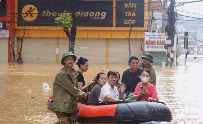 Lực lượng chức năng hỗ trợ người dân di chuyển trong vùng ngập lụt. Ảnh: Chu Hiệu/TTXVN