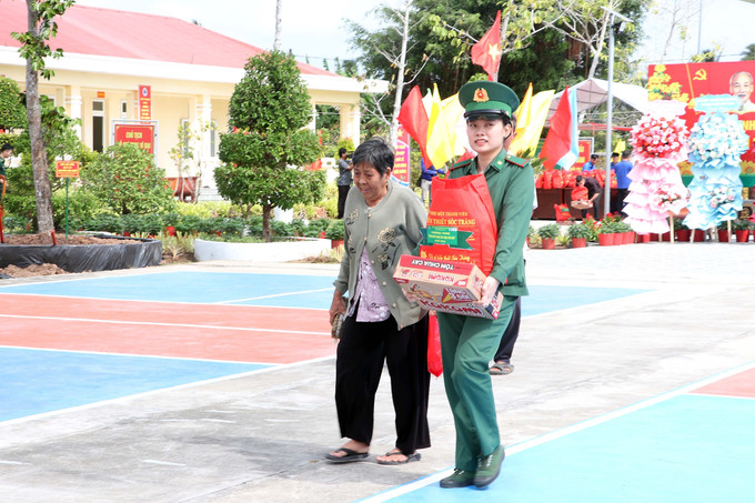 Chiến sĩ Biên phòng hỗ trợ người lớn tuổi mang các phần quà Tết về nhà.