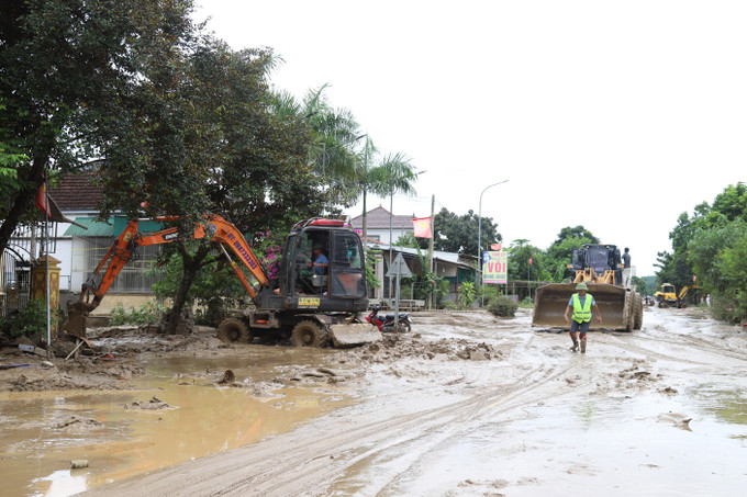 Máy cẩu, máy xúc được huy động tham gia vào việc san ủi bùn đất, sinh lầy tại một điểm ngập trên tuyến quốc lộ 7 qua địa bàn xã Con Cuông, tỉnh Nghệ An. Ảnh: Xuân Tiến/TTXVN nghe-an-250725.jpg