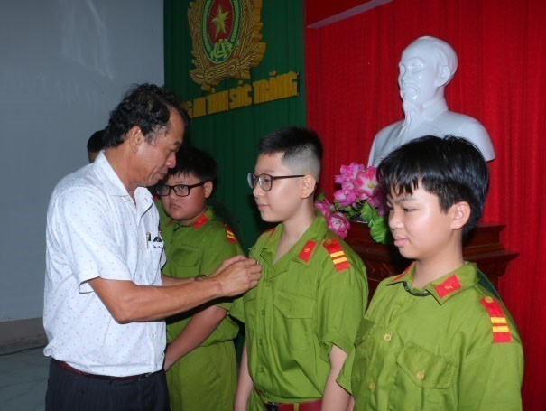 Phó Chủ tịch UBND tỉnh Sóc Trăng Nguyễn Văn Khởi cài hoa cho các em tham gia chương trình. Ảnh: Tuấn Phi/TTXVN st2-030625.jpg