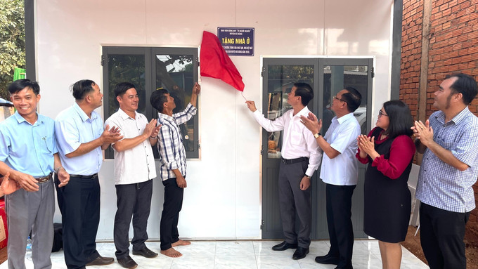 Bí thư Huyện ủy Vũ Lương, Trưởng Ban Chỉ đạo xoá nhà tạm, nhà dột nát huyện Bù Đăng (thứ 4, từ phải qua) thực hiện nghi thức kéo băng trao nhà cho hộ dân có hoàn cảnh khó khăn về nhà ở. Ảnh: TTXVN phát nha-tam-180525.jpg