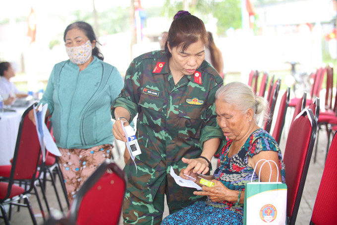 Bác sỹ quân y hướng dẫn người dân uống thuốc.