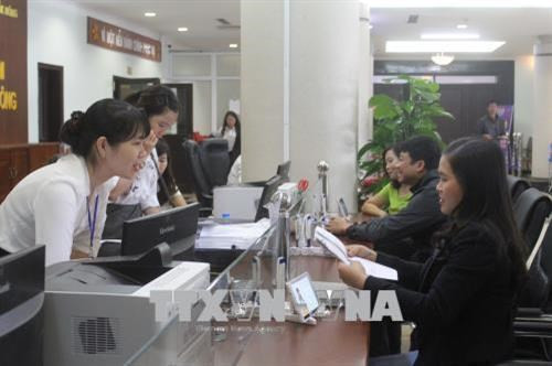 Nhân viên Trung tâm Hành chính công hướng dẫn khách hàng làm thủ tục hành chính. Ảnh: Anh Dũng - TTXVN