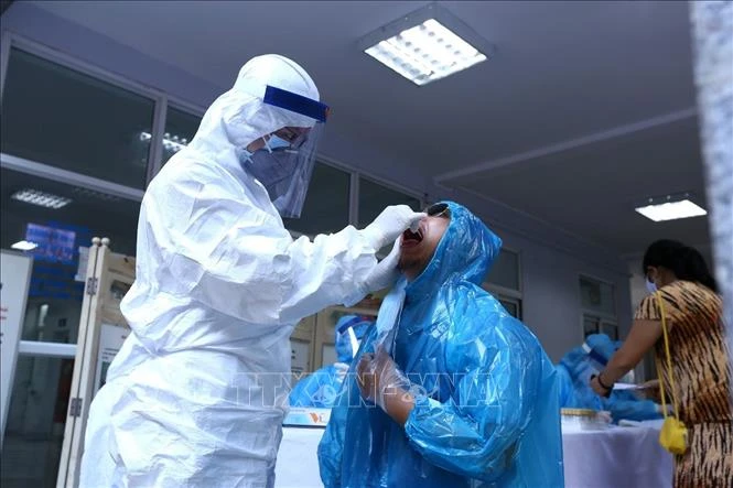 Nhân viên y tế lấy mẫu dịch hầu họng để xét nghiệm bằng phương pháp RT-PCR cho người dân trở về từ Đà Nẵng tại Nhà Hộ Sinh B - Trung Tâm Y Tế quận Hai Bà Trưng. Ảnh: Minh Quyết – TTXVN