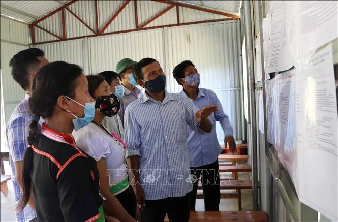 Ông Lý Văn Hom, Bí thư chi bộ bản - người có uy tín bản Tổng Pịt, xã Mường Mô, huyện Nậm Nhùn (Lai Châu), hướng dẫn người dân xem danh sách các ứng cử viên. Ảnh: Việt Hoàng-TTXVN