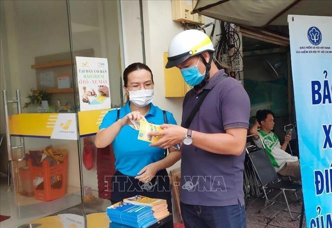 Nhân viên bảo hiểm xã hội tư vấn về chính sách bảo hiểm xã hội, bảo hiểm y tế cho người dân. Ảnh: Đinh Hằng – TTXVN