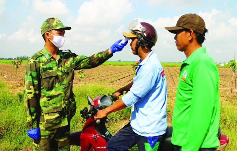 Cán bộ, chiến sĩ phòng, chống dịch COVID-19 số 4 thuộc Đồn Biên phòng quốc tế Vĩnh Xương (Bộ đội Biên phòng tỉnh An Giang) thường xuyên kiểm tra thân nhiệt người dân. Ảnh: Công Mạo – TTXVN