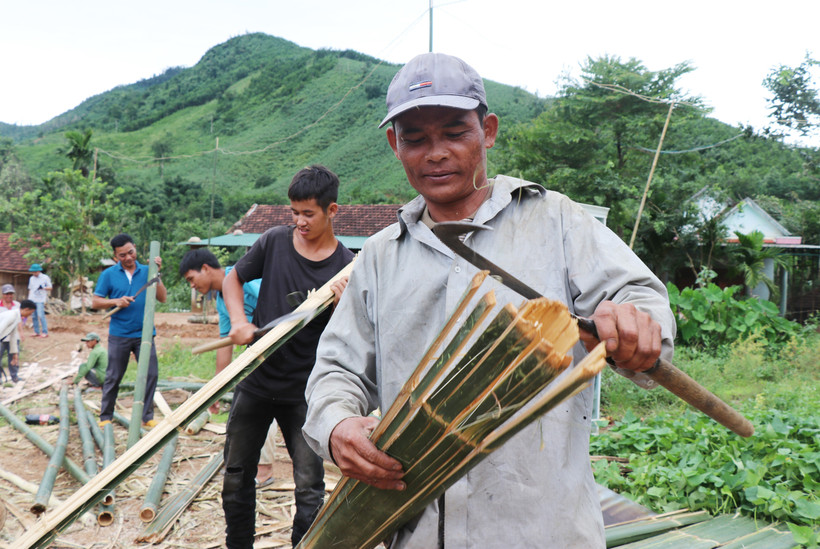 Không ai bảo ai, mỗi người một tay vót tre dựng lại ngôi nhà của gia đình bà Đinh Thị Xấu bị sập sau bão Noru. Ảnh: Phạm Cường - TTXVN