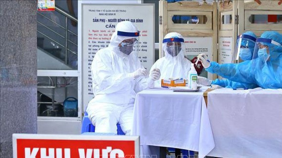 Lấy mẫu xét nghiệm cho người đi từ vùng dịch về. Ảnh: TTXVN