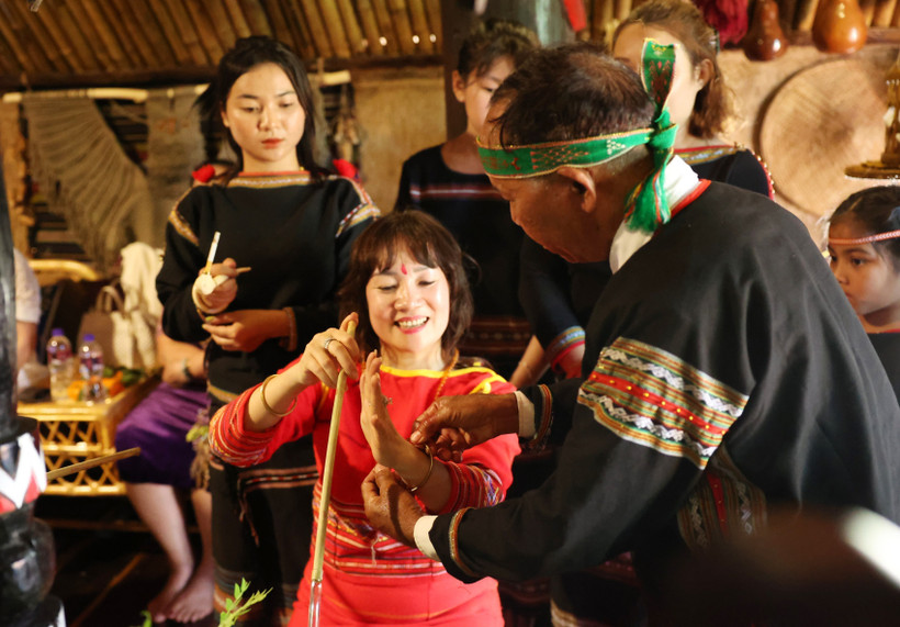 Thầy cúng đeo vòng tay cho chủ nhà để cầu mong sức khỏe và mọi điều tốt đẹp. Ảnh: Tuấn Anh – TTXVN