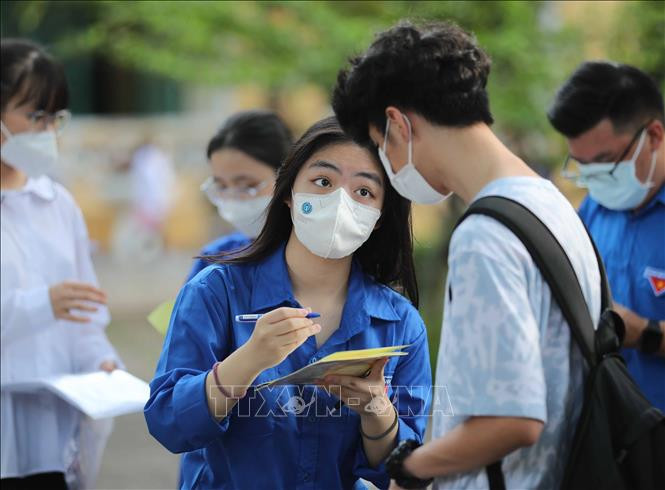 Các thanh niên tình nguyện tại điểm thi Trường THPT Chu Văn An, quận Tây Hồ hỗ trợ ghi thông tin giúp thí sinh gửi đồ ngay từ ngoài cổng trường. Ảnh: Thanh Tùng - TTXVN