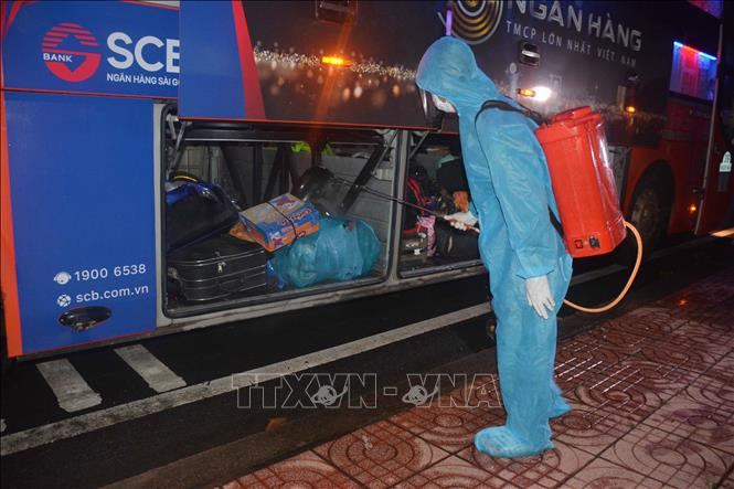 Lực lượng chức năng phun khử khuẩn đồ đạc của công dân trên xe. Ảnh: Hoài Thu – TTXVN.