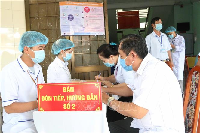 Hướng dẫn người được tiêm điền phiếu sàng lọc. Ảnh: Thanh Hòa- TTXVN