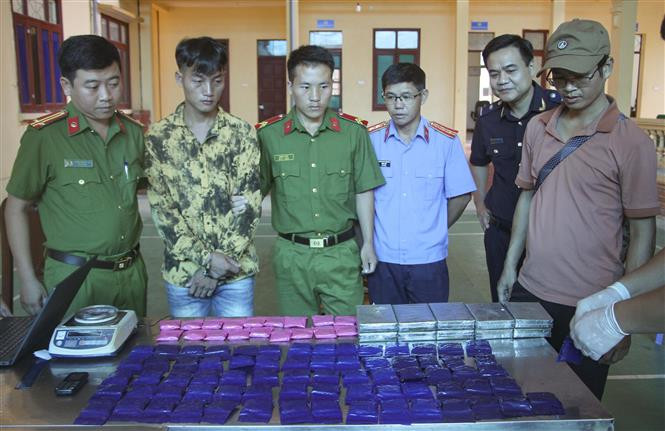 Đối tượng Lầu A Co (áo vàng loang đen, thứ hai từ trái sang) cùng tang vật tại cơ quan điều tra. Ảnh: TTXVN phát