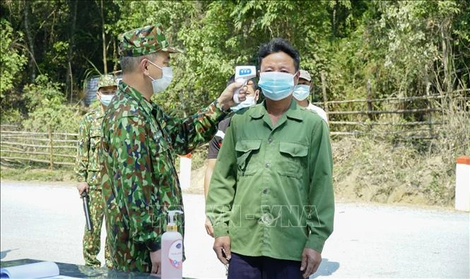 Kiểm tra thân nhiệt đối với người dân qua lại khu vực biên giới. Ảnh: Xuân Tư – TTXVN