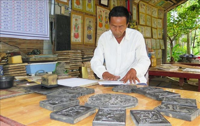Nghệ nhân Kỳ Hữu Phước in tranh. Ảnh: Tường Vi – TTXVN