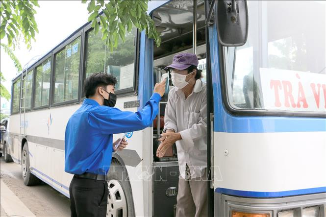 Đoàn viên, thanh niên kiểm tra thân nhiệt cho người dân vào tỉnh Vĩnh Long. Ảnh: Lê Thúy Hằng - TTXVN