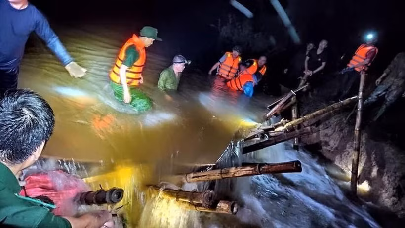 Lực lượng chức năng và người dân dầm mình trong nước lũ để cứu đê trong đêm. Ảnh: TTXVN phát
