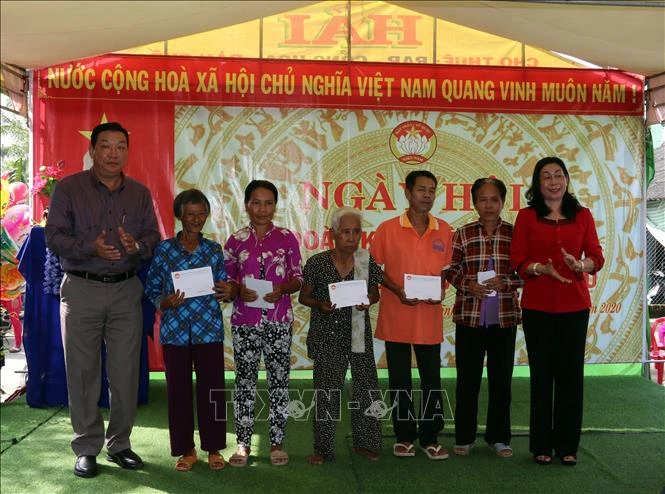 Bà Lê Thị Vệ (áo đỏ), Chủ tịch Ủy ban Mặt trận Tổ quốc Việt Nam tỉnh Kiên Giang tặng quà cho bà con dân tộc Khmer nghèo trên địa bàn dân cư ấp Vĩnh Đằng. Ảnh: Lê Sen - TTXVN